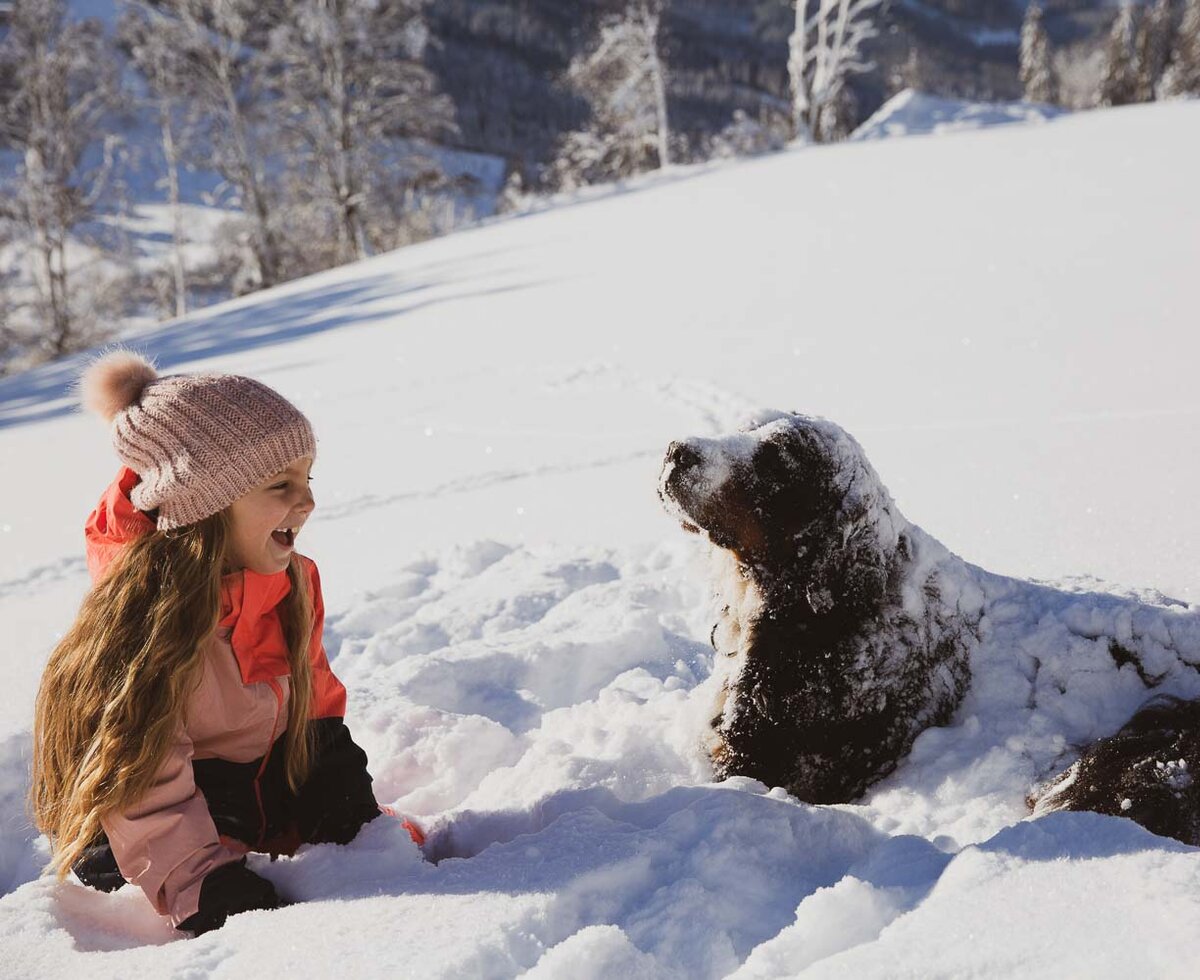 Mädchen spielt mit Hund im Schnee | © Urlaub am Bauernhof / Punkt & Komma Mädchen spielt mit Hund im Schnee am Proneben Gut in Mühlbach am Hochkönig | © Urlaub am Bauernhof / Punkt & Komma